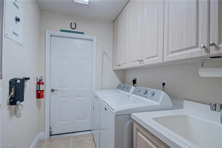 Laundry area with washer and dryer, cabinet space, and light tile patterned floors