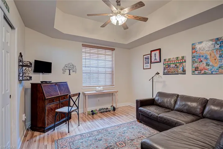 Office with a raised ceiling, hardwood / wood-style floors, and a ceiling fan