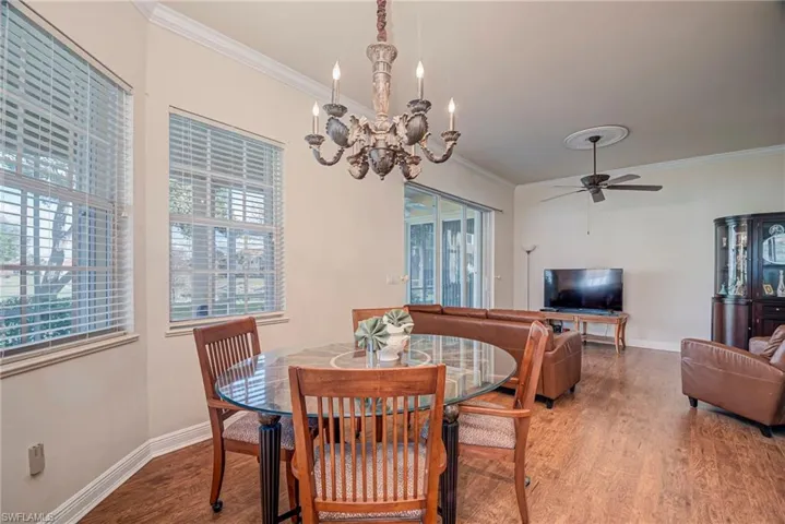 Dining room with crown molding, wood finished floors, a ceiling fan, and a chandelier