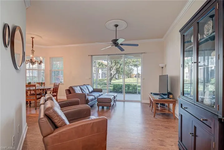 Living area featuring crown molding, light wood-type flooring, healthy amount of natural light, a ceiling fan, and a chandelier