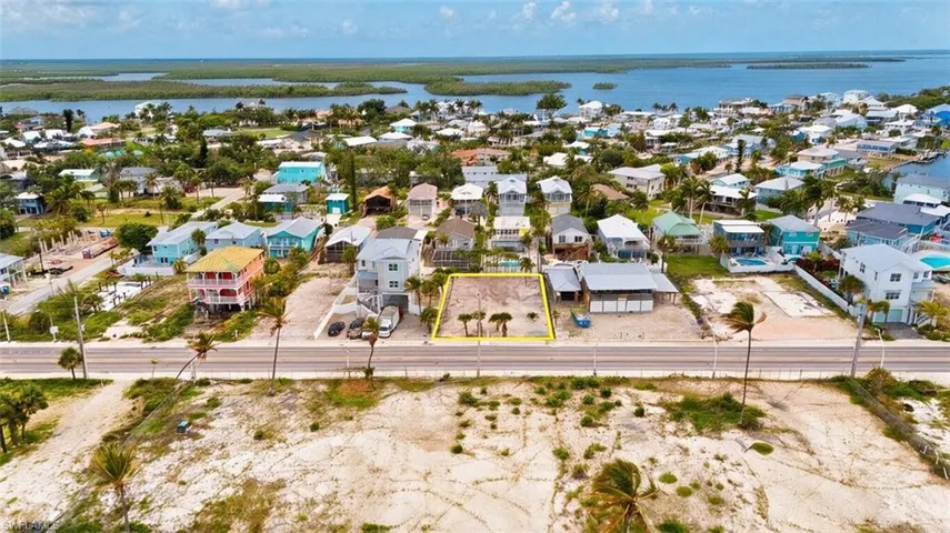 VIRTUALLY ENHANCED - Vacant lot featuring existing palm trees and direct road frontage