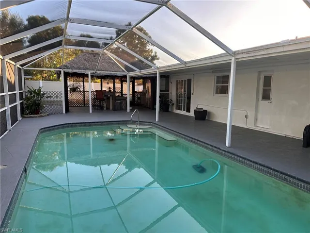 View of swimming pool featuring a patio area, glass enclosure, and a sunroom