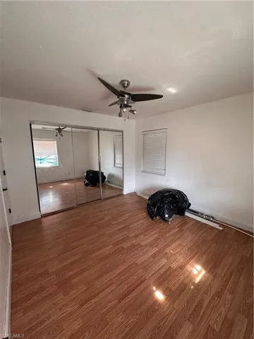 Bedroom with a ceiling fan, light wood finished floors, ensuite bath, and arched walkways