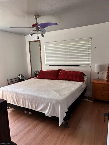 Bedroom with wood finished floors, ceiling fan, and a textured ceiling