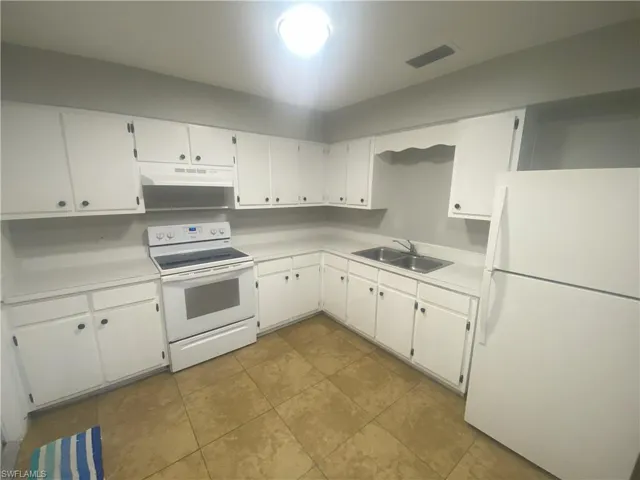 Kitchen featuring white cabinetry with dark hardware, white countertops, dual basin stainless steel sink, and tile flooring