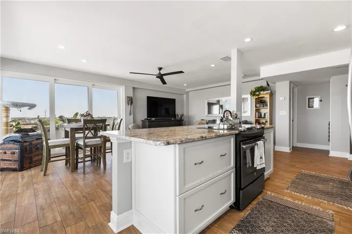 Kitchen with a kitchen island, ceiling fan, white cabinets, light hardwood / wood-style floors, and black electric range oven