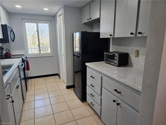 Kitchen featuring stainless steel appliances, light tile patterned flooring, and gray cabinetry