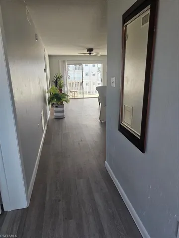 Hallway with dark wood-type flooring and a textured wall