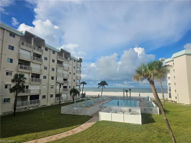 Community pool with view of water and beach, a yard, and a patio area