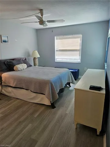 Bedroom with ceiling fan, a textured ceiling, and wood finished floors