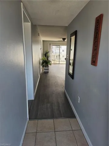 Hallway featuring light tile patterned floors and a textured ceiling