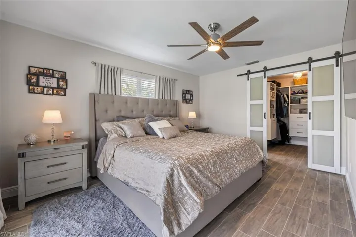 Bedroom with ceiling fan, a barn door, a closet, and a spacious closet