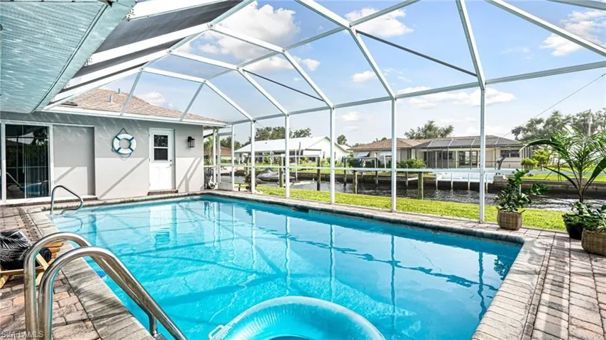 View of pool featuring a patio area, a water view, and glass enclosure