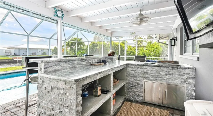 View of patio featuring area for grilling, a lanai, and an outdoor bar