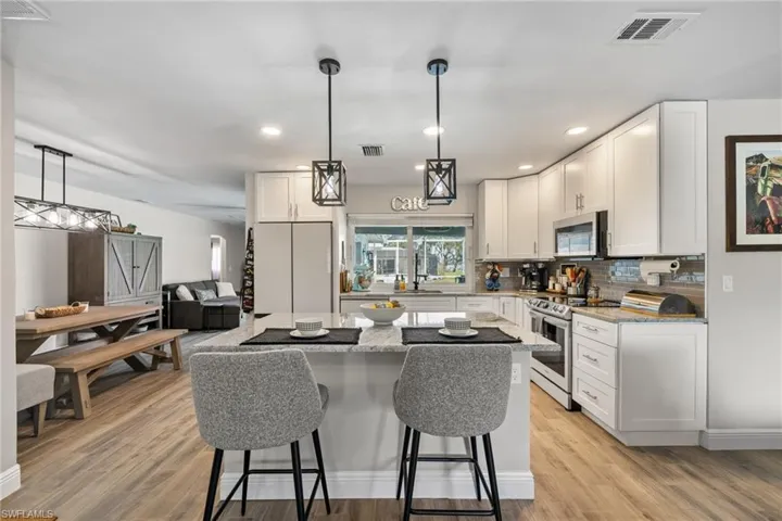 Kitchen featuring light stone countertops, stainless steel appliances, and white cabinets