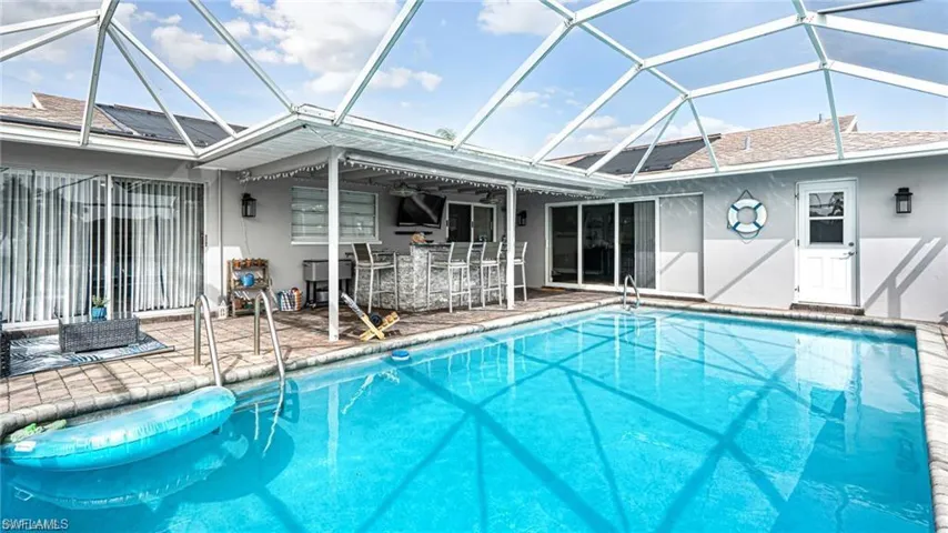 View of swimming pool featuring a patio, a lanai, and an outdoor bar