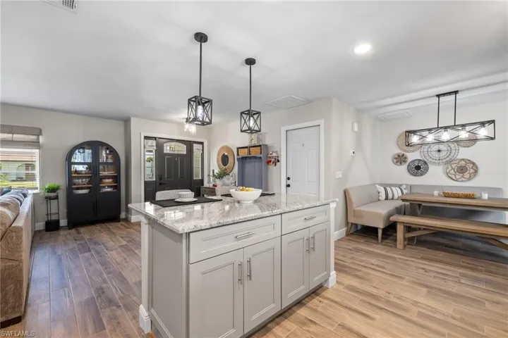 Kitchen with light stone counters, decorative light fixtures, light hardwood / wood-style flooring, and a center island