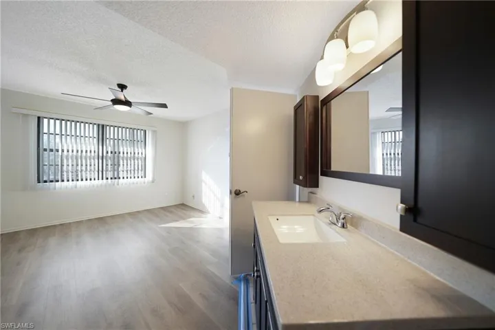 Bathroom featuring ceiling fan, vanity, wood-type flooring, and a textured ceiling