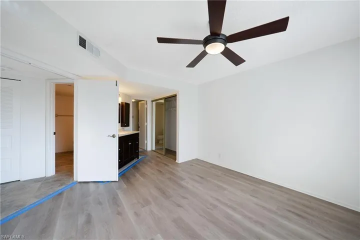 Unfurnished bedroom with ceiling fan, light hardwood / wood-style floors, a closet, and ensuite bath