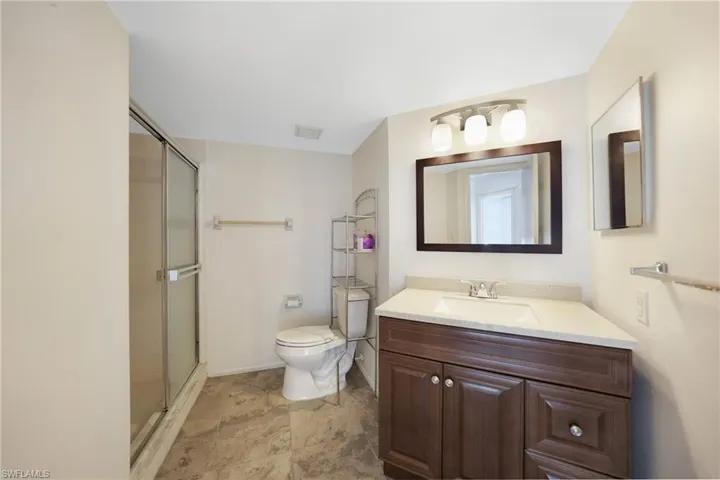 Bathroom featuring walk in shower, vanity, and toilet