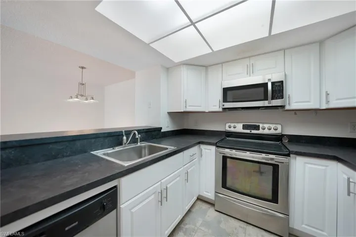 Kitchen with pendant lighting, sink, white cabinetry, and stainless steel appliances