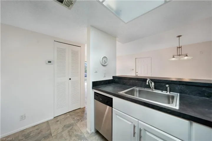 Kitchen with white cabinetry, sink, stainless steel dishwasher, a textured ceiling, and decorative light fixtures