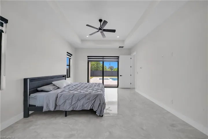 Spacious room with tray ceiling, recessed lighting, and a modern ceiling fan
