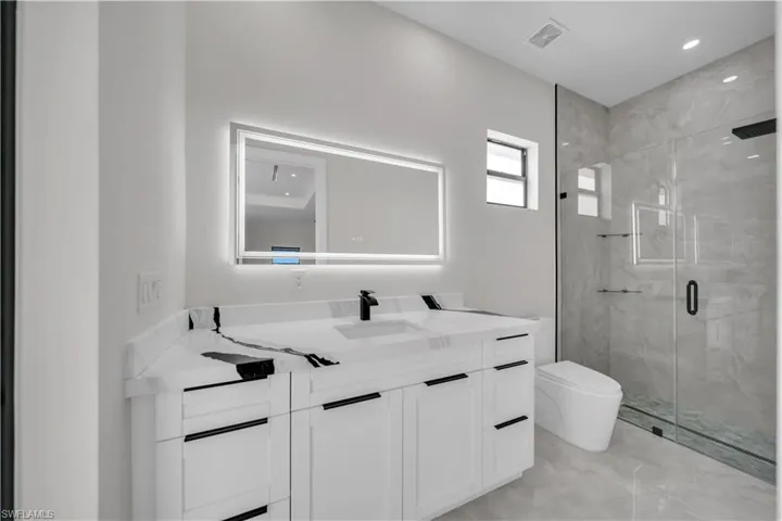 Contemporary bathroom featuring a spacious vanity with white cabinetry and black hardware