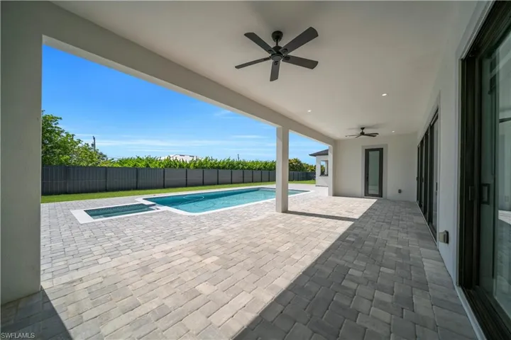 Expansive covered patio featuring paver flooring, dual ceiling fans, and recessed lighting