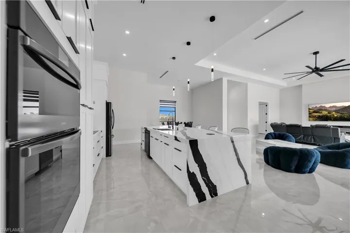 Gourmet kitchen with double wall ovens, white cabinetry, and a waterfall island featuring a striking black and white stone countertop