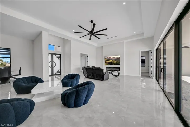 Expansive living area featuring large format light gray tile flooring, recessed lighting, and a modern ceiling fan
