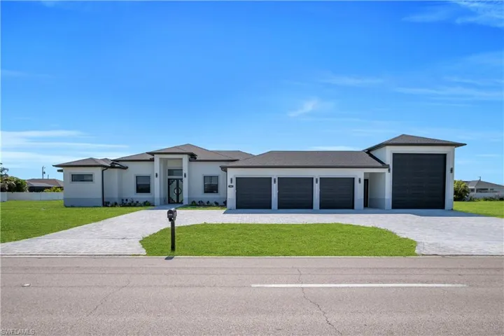 Contemporary stucco exterior with a dark shingle roof and contrasting dark garage doors