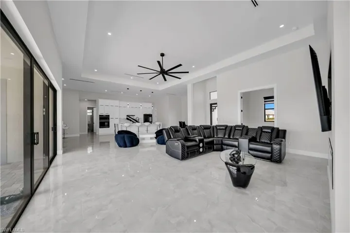 Open-concept living space featuring high ceilings with recessed lighting, large format light-toned tile flooring, and multi-panel sliding glass doors