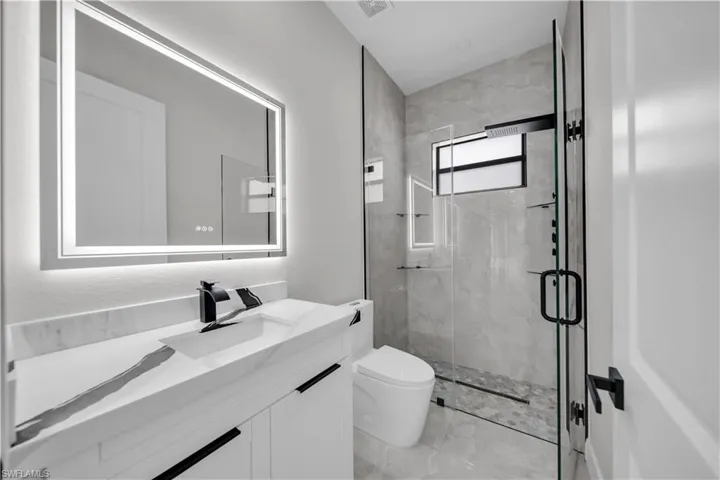 Contemporary bathroom featuring a floating white vanity with a rectangular integrated sink, a sleek black faucet, and a backlit mirror