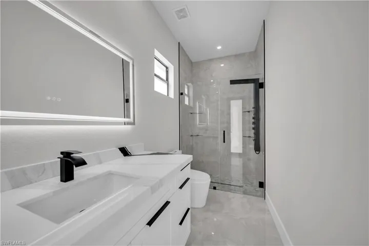 Bathroom featuring a large vanity with a rectangular undermount sink, a matte black faucet, and a quartz countertop