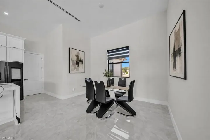 Open-concept dining area featuring light-toned large format tile flooring and a modern window with horizontal blinds