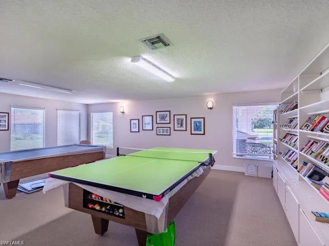 Recreation room with a wealth of natural light, carpet flooring, visible vents, and a textured ceiling