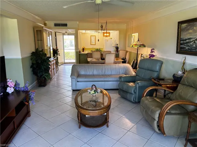 Living area with crown molding, visible vents, and a textured ceiling