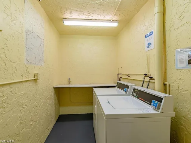 Community laundry room featuring a textured wall and washer and clothes dryer
