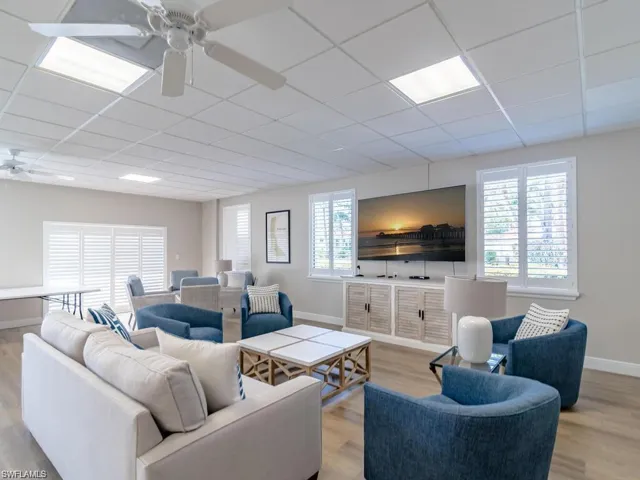 Living room with a paneled ceiling, wood finished floors, ceiling fan, and baseboards