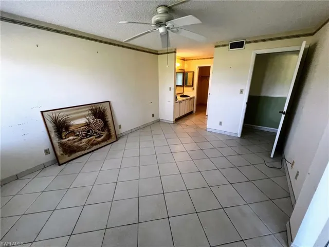 Unfurnished living room with visible vents, a textured ceiling, baseboards, and ceiling fan