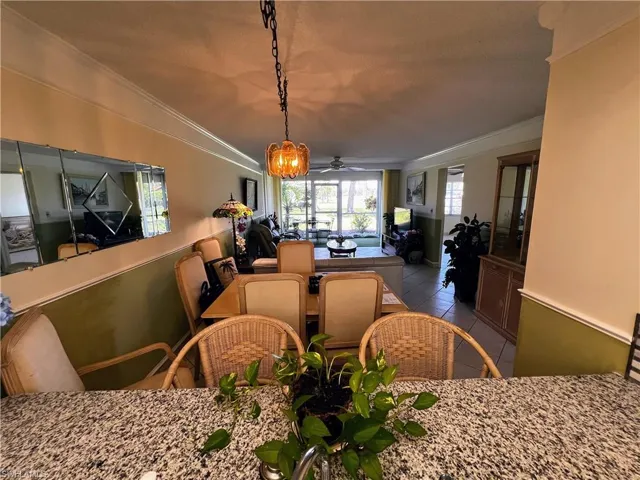 Tiled dining area with crown molding and ceiling fan