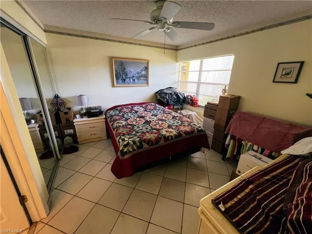 Bedroom featuring a closet, a textured ceiling, a ceiling fan, and light tile patterned flooring
