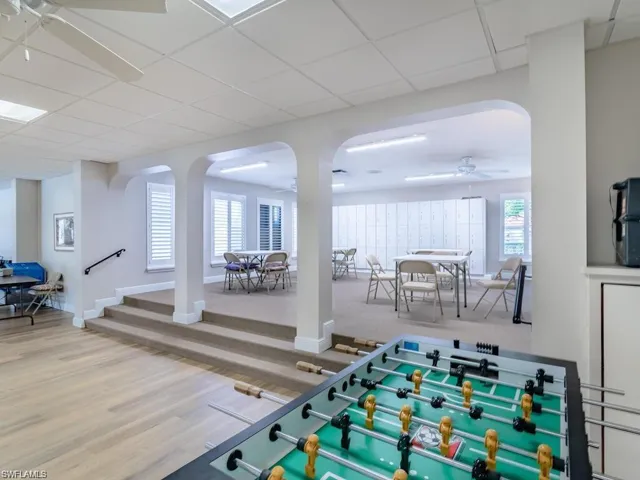 Recreation room featuring a drop ceiling, arched walkways, wood finished floors, and a ceiling fan