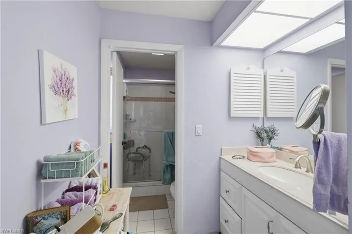 Bathroom featuring a single vanity with an integrated sink, white cabinetry, and a framed mirror