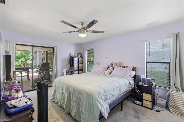 Carpeted room featuring a ceiling fan, sliding glass doors, and a window with blinds