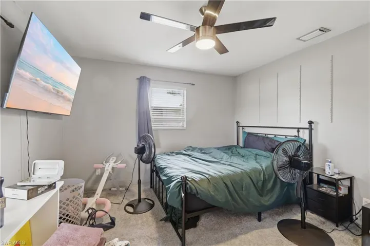 Ceiling fan with integrated lighting, wall-mounted shelving tracks, window with horizontal blinds, and carpeting