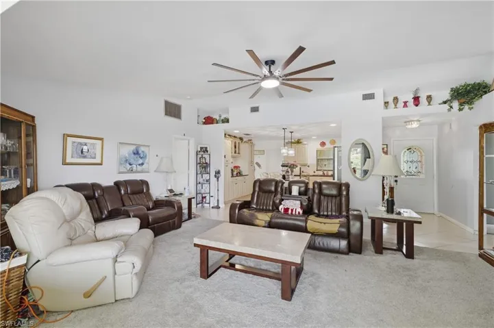 Spacious living area featuring soft carpeting, a ceiling fan with integrated lighting, and decorative wall niches