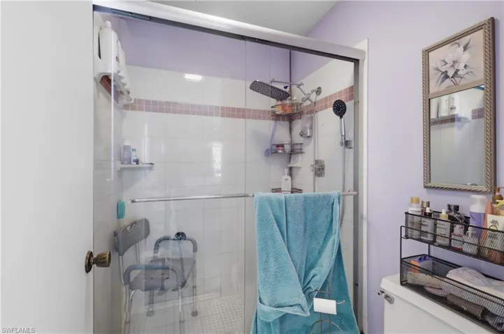 Glass-enclosed shower with white tiled walls and decorative accent band