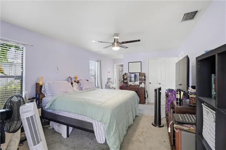 Vaulted ceiling with a contemporary ceiling fan, dual windows with blinds, and carpeted flooring